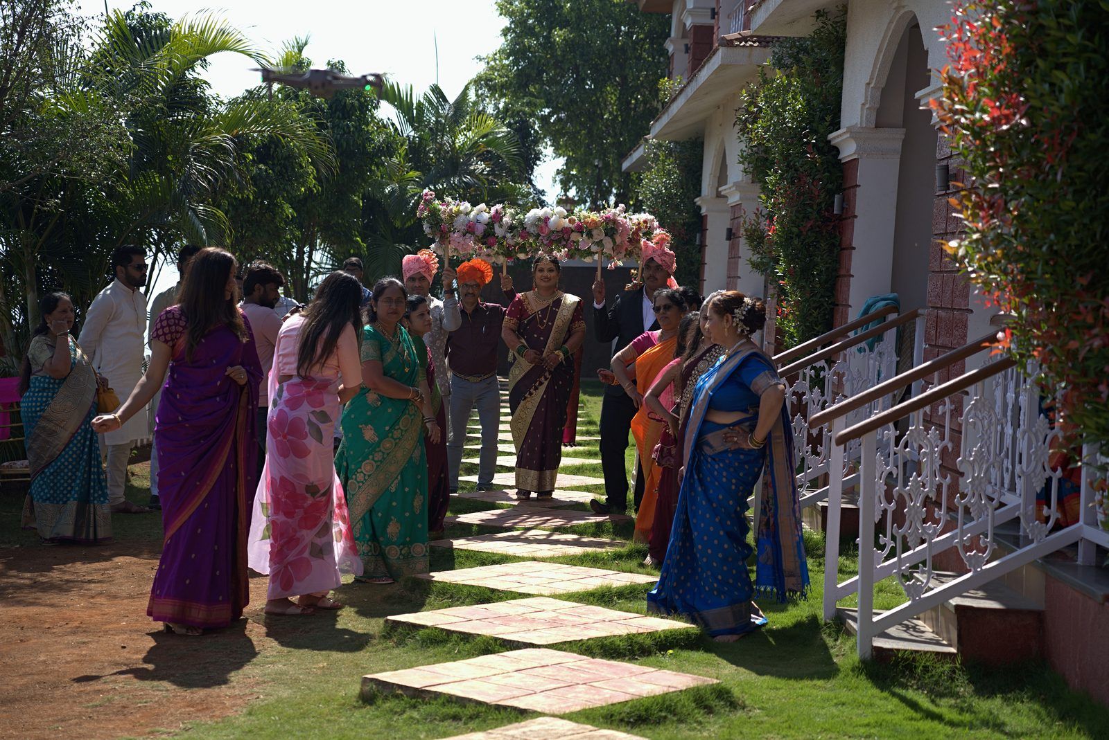 A sample straight out of the pipeline, in ceremony order: arrival at the resort, a bouquet held in mehndi-decorated hands from Seemant Poojan, a Haldi portrait of the groom in a yellow kurta beside a flowering hedge, Lagna Vidhi, the bride's entry at Mangalashtak, the Varat shot from the drone, reception portraits (photographer-graded passthrough), and a Sangeet stage performance under the adaptive-gamma night grade.