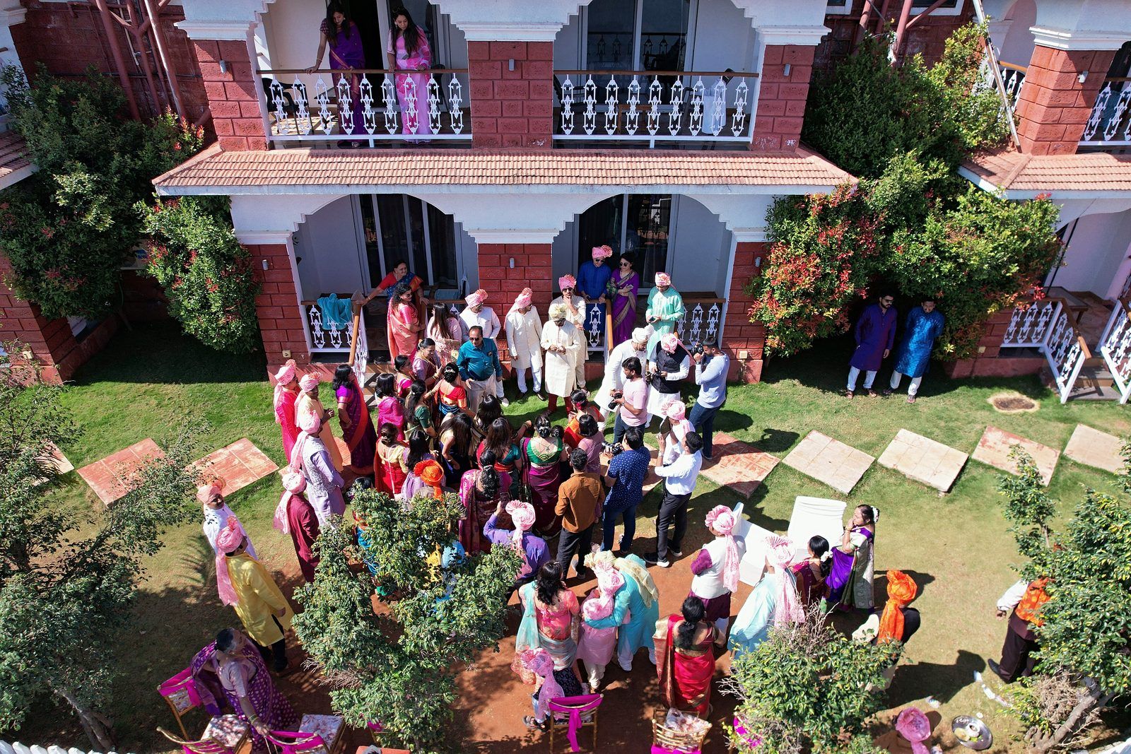 A sample straight out of the pipeline, in ceremony order: arrival at the resort, a bouquet held in mehndi-decorated hands from Seemant Poojan, a Haldi portrait of the groom in a yellow kurta beside a flowering hedge, Lagna Vidhi, the bride's entry at Mangalashtak, the Varat shot from the drone, reception portraits (photographer-graded passthrough), and a Sangeet stage performance under the adaptive-gamma night grade.